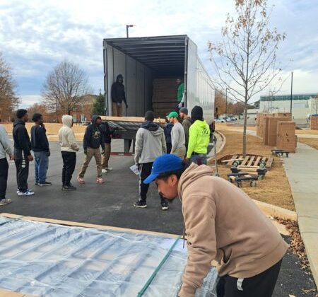 Corporate movers from Muscle 4 Moving unloading freight and pallets from a semi-truck at the University of Alabama In Huntsville.